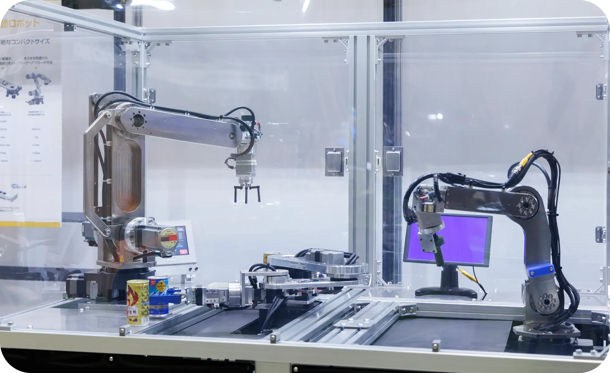 ガラスケースの中で精密な動きを見せる、2台の産業用ロボットアーム。