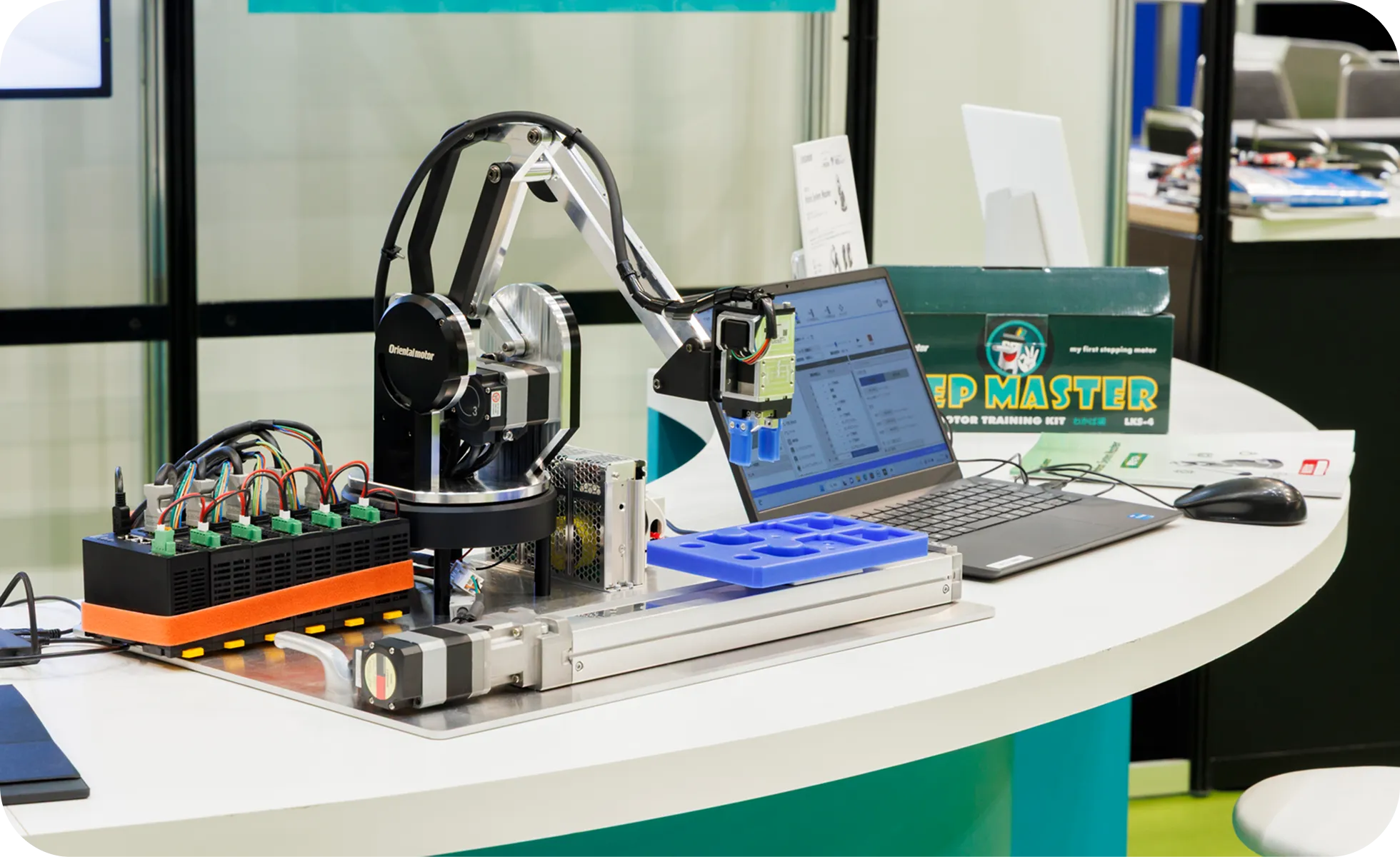 デスクの上に設置された、小型ロボットアームと制御用ノートPCのデモ機。