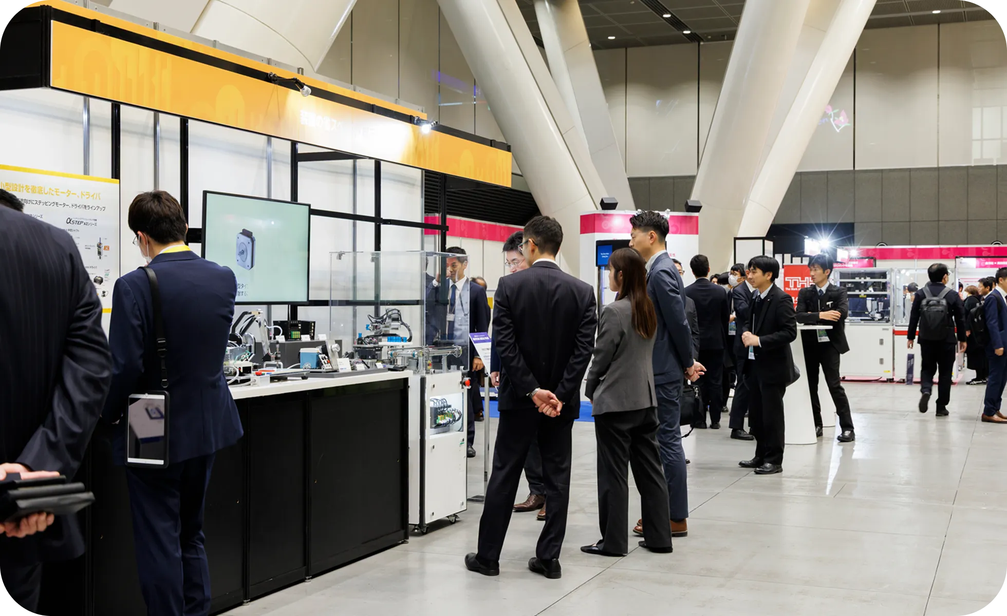 大型モニターを見ながら、スタッフから製品説明を受けるスーツ姿の来場者。